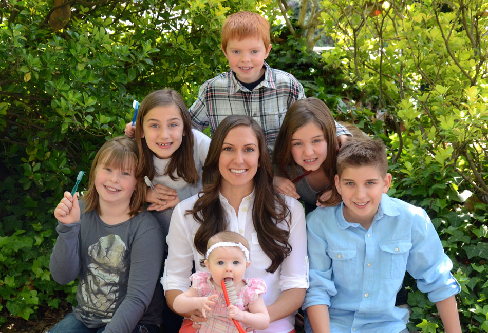 Pediatric dentist Dr. Patrice Espinosa and a group of kids holding toothbrushes